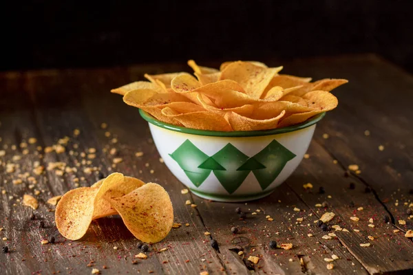 Crispy potato chips in a wicker bowl on wooden a table