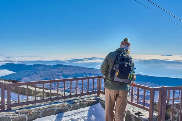 Chica vestida de invierno mirando las vistas desde la cima de la montaña con un fondo azul del cielo — Foto de Stock