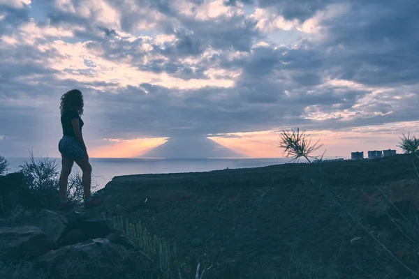 Kızın silueti Tenerife 'deki bir vadinin tepesinden gün batımını izliyor.