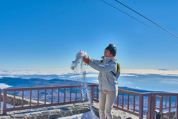 Kız dağda karla oynarken eğleniyor.