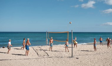 İnsanlar güneşli bir günde plajda voleybol oynuyorlar.