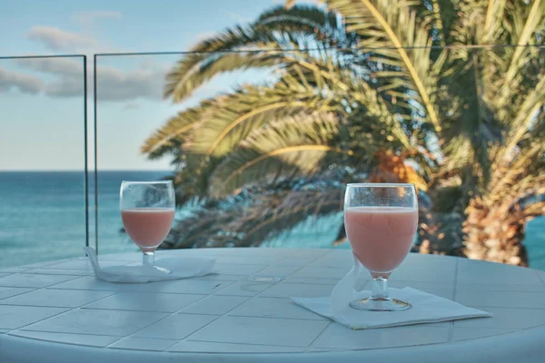 Palmiye ağaçları ve deniz manzaralı bir terasta yemek hazırlığı.