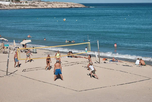 İnsanlar güneşli bir günde plajda voleybol oynuyorlar.