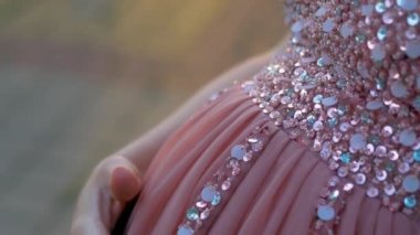 Pembe elbiseli karnını okşuyor.