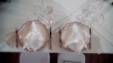 Güzel peçeteleri ve pembe tabakları olan beyaz bir masa örtüsü.