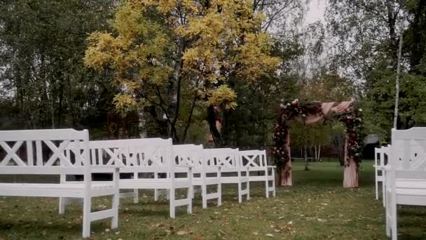 在秋天的森林里 有一个装饰着花卉的拱门供登记 旁边是白色的老式长椅 — 图库视频影像
