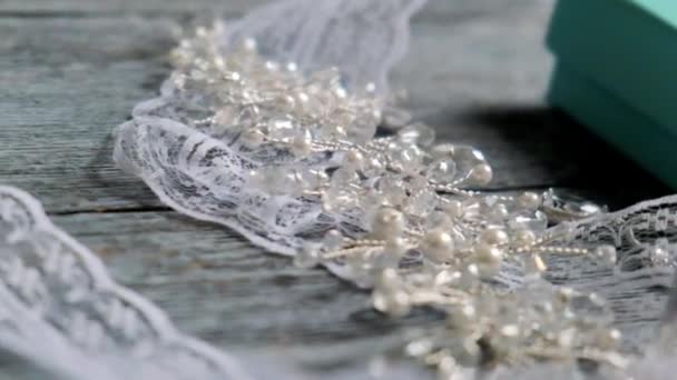 白いかぎ針編みのリボンは軽いテーブルの上にあります 金属の葉の小枝で作られた髪飾り — ストック動画