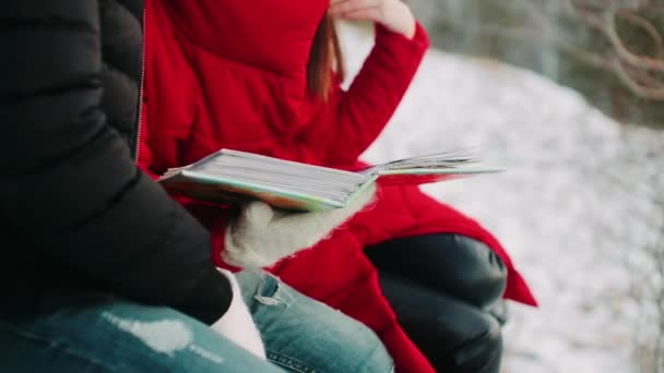 Ένας Άντρας Και Ένα Κορίτσι Κοιτάζουν Ένα Άλμπουμ Φωτογραφιών Χειμώνα — Αρχείο Βίντεο