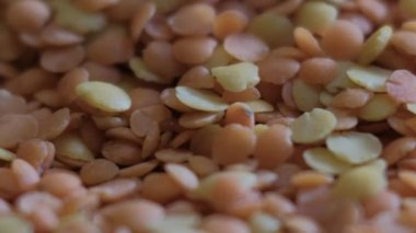 Bir yığın sarı-turuncu mercimek dibe düşüyor. Macro Lentils 4k. diyet yemek geçmişi. Gurme ve organik gıda konsepti. İçkiler ve yemek geçmişi. gastronomik video.