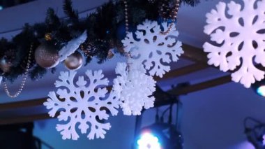 Kar taneleri şeklinde Noel süsleri bir projektörün yanında asılı duruyor.