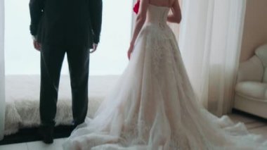 Gelin ve damat pencereden dışarı bakar sırtlarını döner ve birbirlerinin ellerini tutarlar.