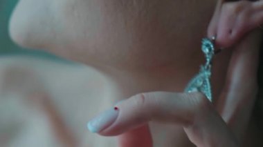 Parmakları ile dokunarak küpe gelin düzeltir.