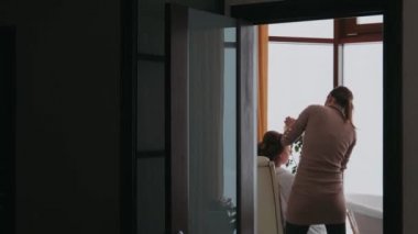 Kışın bir sandalyede oturan kız pencereden dışarı bakıyor.