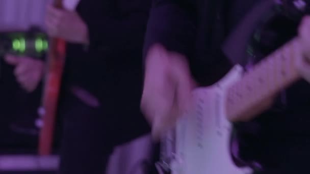 Un homme joue sur une guitare électrique blanche dans un club 