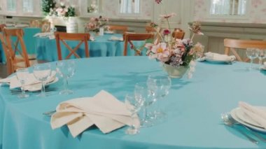 winter decor of a wedding banquet hall with blue tablecloths and beautiful soft pink flowers
