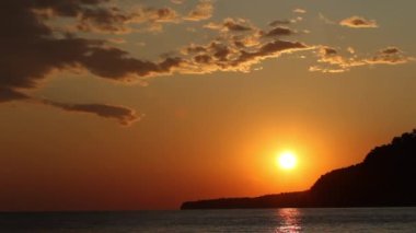 Denizde kızıl gün batımı. Güneş ufukta beliriyor. Kızıl gökyüzü, sarı güneş ve inanılmaz deniz. Yaz günbatımı deniz manzarası. Atlantik Okyanusu plaj günbatımı. Güneş dönen bulutlarda. İnanılmaz doğal gün batımları.