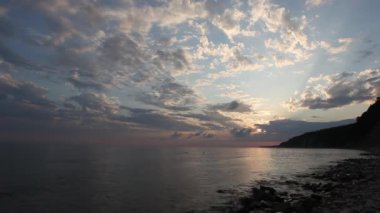 Denizde kızıl gün batımı. Güneş ufukta beliriyor. Kızıl gökyüzü, sarı güneş ve inanılmaz deniz. Yaz günbatımı deniz manzarası. Atlantik Okyanusu plaj günbatımı. Güneş dönen bulutlarda. İnanılmaz doğal gün batımları.