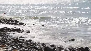 Deniz öğleden sonra yakın çekim. Dalgalar taşlara sıçrıyor