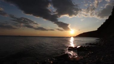 Denizde kızıl gün batımı. Güneş ufukta beliriyor. Kızıl gökyüzü, sarı güneş ve inanılmaz deniz. Yaz günbatımı deniz manzarası. Atlantik Okyanusu plaj günbatımı. Güneş dönen bulutlarda. İnanılmaz doğal gün batımları.