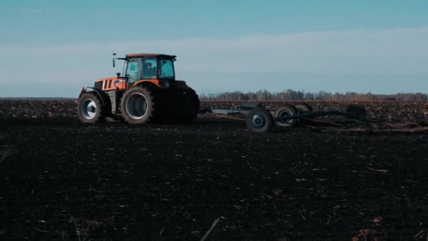 Traktor Ett Fält Våren Drar Svart Jord Mot Klarblå Himmel — Stockvideo