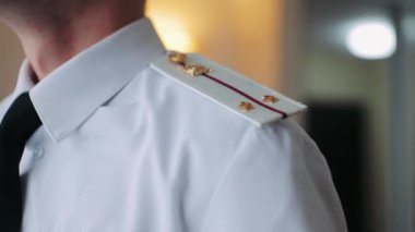 Beyaz tişörtlü askeri apoletler.