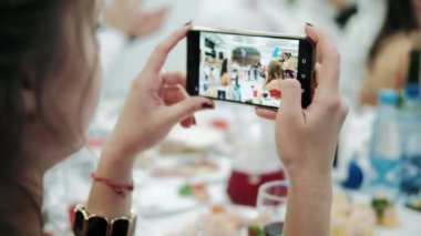 Kız, ziyafette olanları telefona taşır.