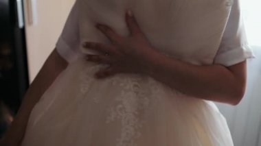 Gelinlik deneyen güzel genç bir kadın aynaya bakıyor. Kıyafet seçiyor. Kıyafetler giyiyor.