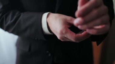 Adam beyaz bir gömlek giyip pencerede kelepçeleri düzeltiyor.