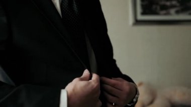 Adam beyaz bir gömlek giyip pencerede kelepçeleri düzeltiyor.