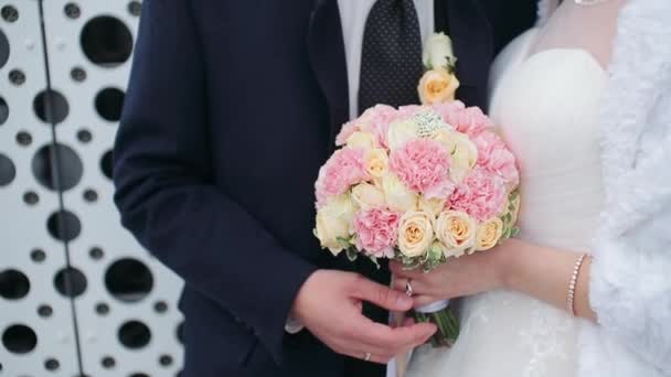 スーツの結婚式で新郎はピンクの花束と白いドレスで妊娠中の花嫁を抱擁します 妊娠中の腹を撫でる男 — ストック動画