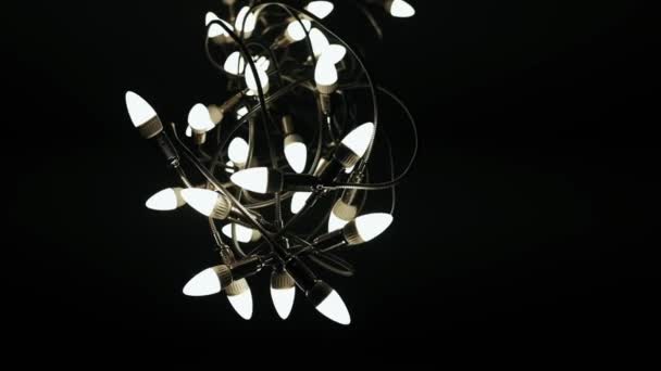 黑色背景上的吊灯灯泡相互交织成一大束大的不同寻常的吊灯 — 图库视频影像
