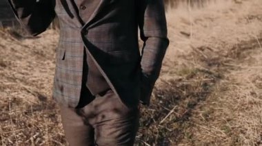 Erkek bacakları, sonbahar çimlerinde güzel bir takım elbiseyle yürür.