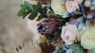 Boho düğün buketi. Rüzgarda sallanan büyük beyaz bir tüy. Boho düğün buketi doğada bir sandalyede yatıyor.