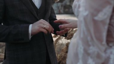 Gençler törende birbirlerine yüzük takarlar. Eller yakın plan.