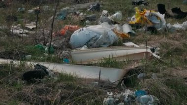 Yerdeki plastik çöpler. İnsanların neden olduğu çevreye zarar veriyorlar. Yerde çöp var. Genç yeşil çimenlerin yanında..