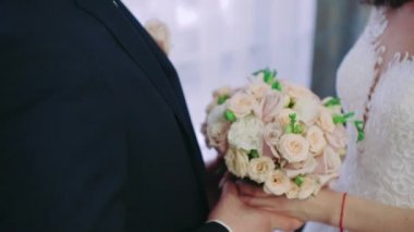 Gelin ve damat buketlerle el ele tutuşuyorlar.