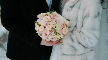 Gelin ve damat buketlerle el ele tutuşuyorlar.