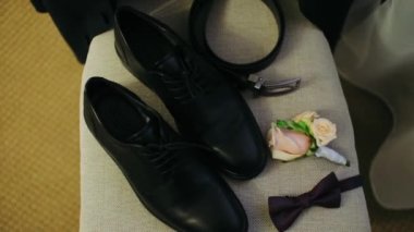 Siyah adamın ayakkabıları, kelebek kayışı ve sandalyenin üzerinde bir düğme deliği var.