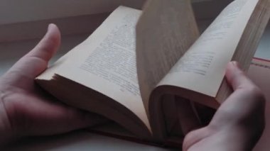 Kendi kendini eğitme. Evde ders çalışıyorum. Bir kız yeşil baharda pencerenin yanında bir kitap okuyor..