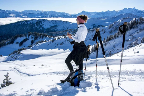 Sportive woman snow shoeing enjoying the view of the winter mountain panorama — ストック写真