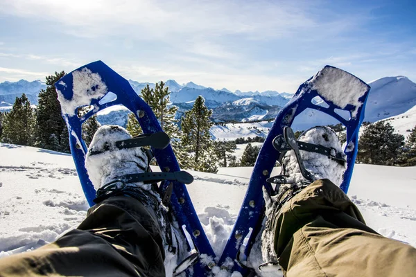 Point of view of snow shoes, sitting in the snow in front of mountain panorama — ストック写真