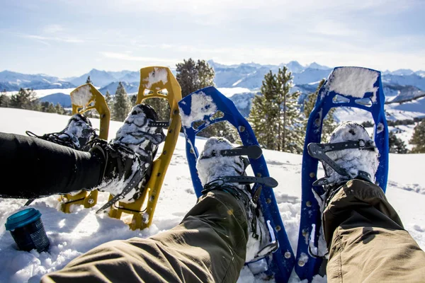 Point of view of snow shoes, sitting in the snow in front of mountain panorama — ストック写真