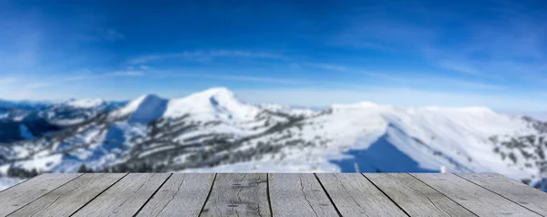 wooden display shelf table top against blurred snow covered mountain panorama