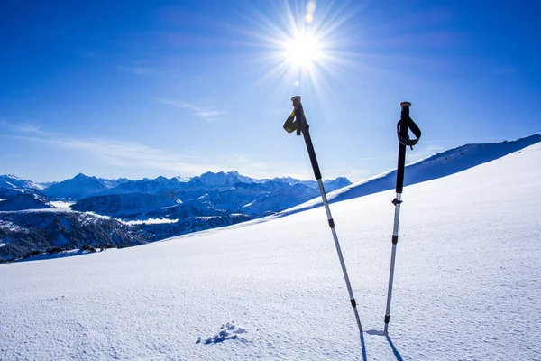 Vintersportkoncept. skidstavar i djup snö mot fjällpanorama med blå himmel — Stockfoto