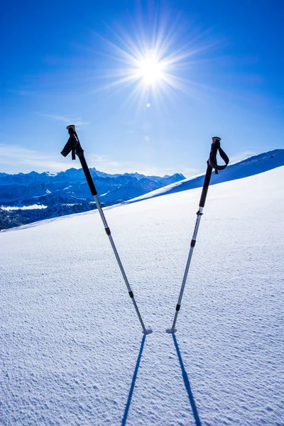 Vintersportkoncept. skidstavar i djup snö mot fjällpanorama med blå himmel — Stockfoto