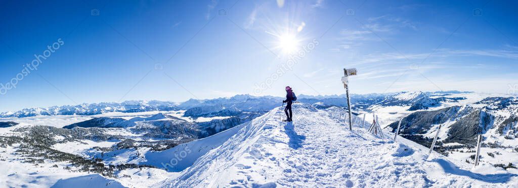 snow shoe hiker a the summit of the snowy mountain. panoramic picture of winter hiker at the top of the hill. gorgeous swiss alps mountain panorama with sun and blue sky