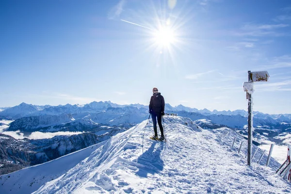 スノーシューハイカーは雪の山の頂上です丘の上の冬のハイカーのパノラマ写真です豪華なスイスアルプスの山のパノラマと太陽と青い空 — ストック写真