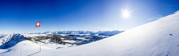 Neve coberto alpes suíços gama de montanhas com bandeira nacional suíço contra o céu azul, com espaço de cópia — Fotografia de Stock