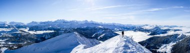 Dağcı, mavi kar kaplı dağ katmanlarına karşı zirvede. Karlı dağın zirvesinde panoramik resim. panoramik kış manzarası, güneşli mavi gökyüzü