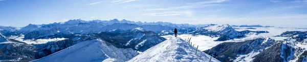 Alpinista na szczycie z niebieskimi pokrytymi śniegiem warstwami górskimi. panoramiczny obraz na szczycie zaśnieżonej góry. panoramiczny zimowy krajobraz, słoneczne błękitne niebo — Zdjęcie stockowe